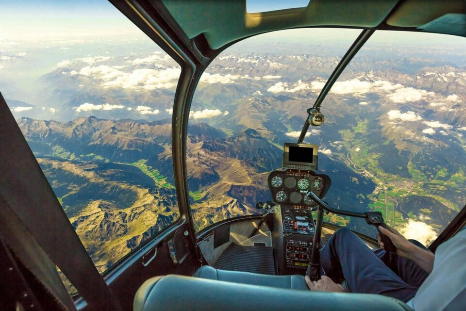 Cockpit View From A Helicopter Over Mountains And Valleys, Showing Pil